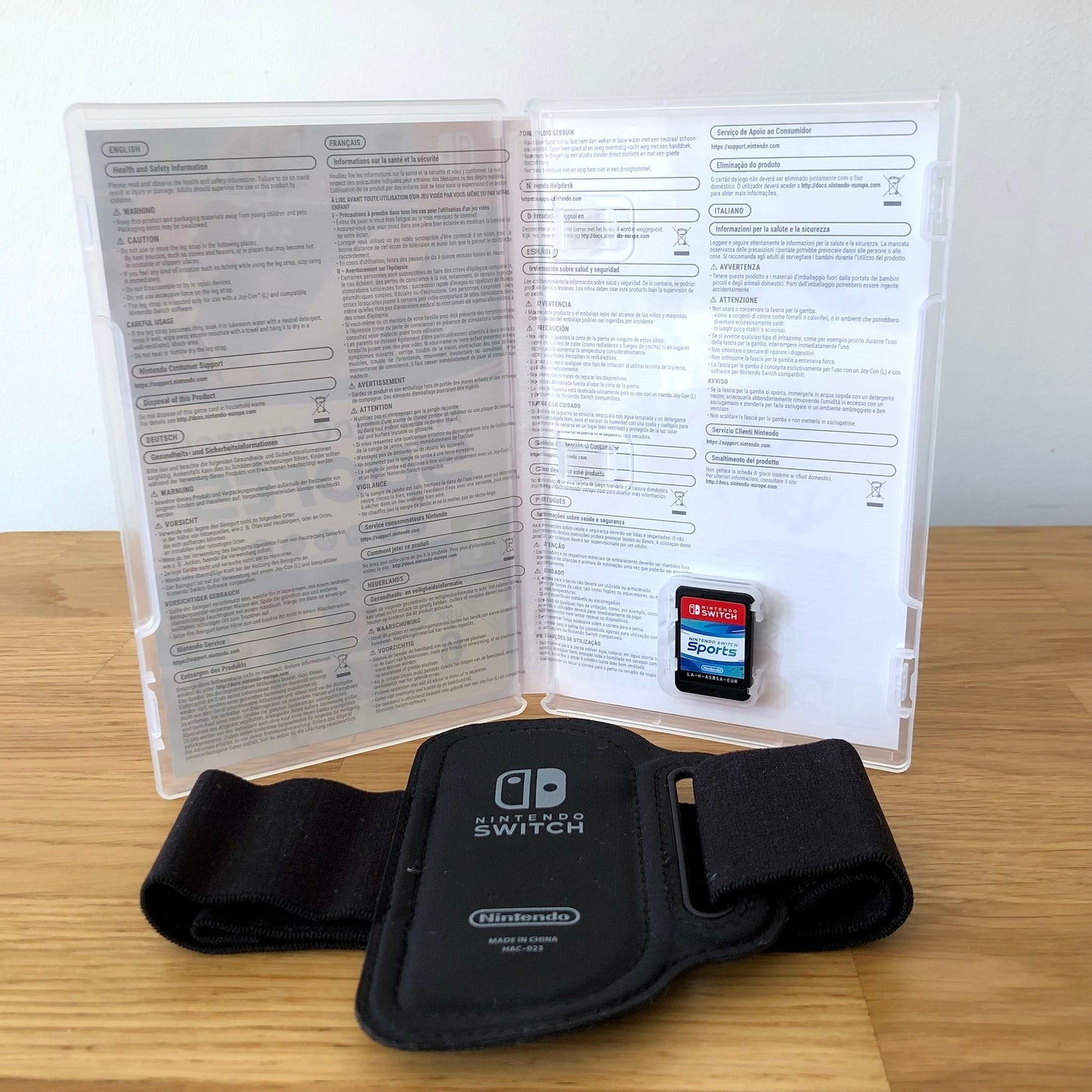 Inside the case of Nintendo Switch Sports for Nintendo Switch, showing the game cartridge in its slot and leg strap below.