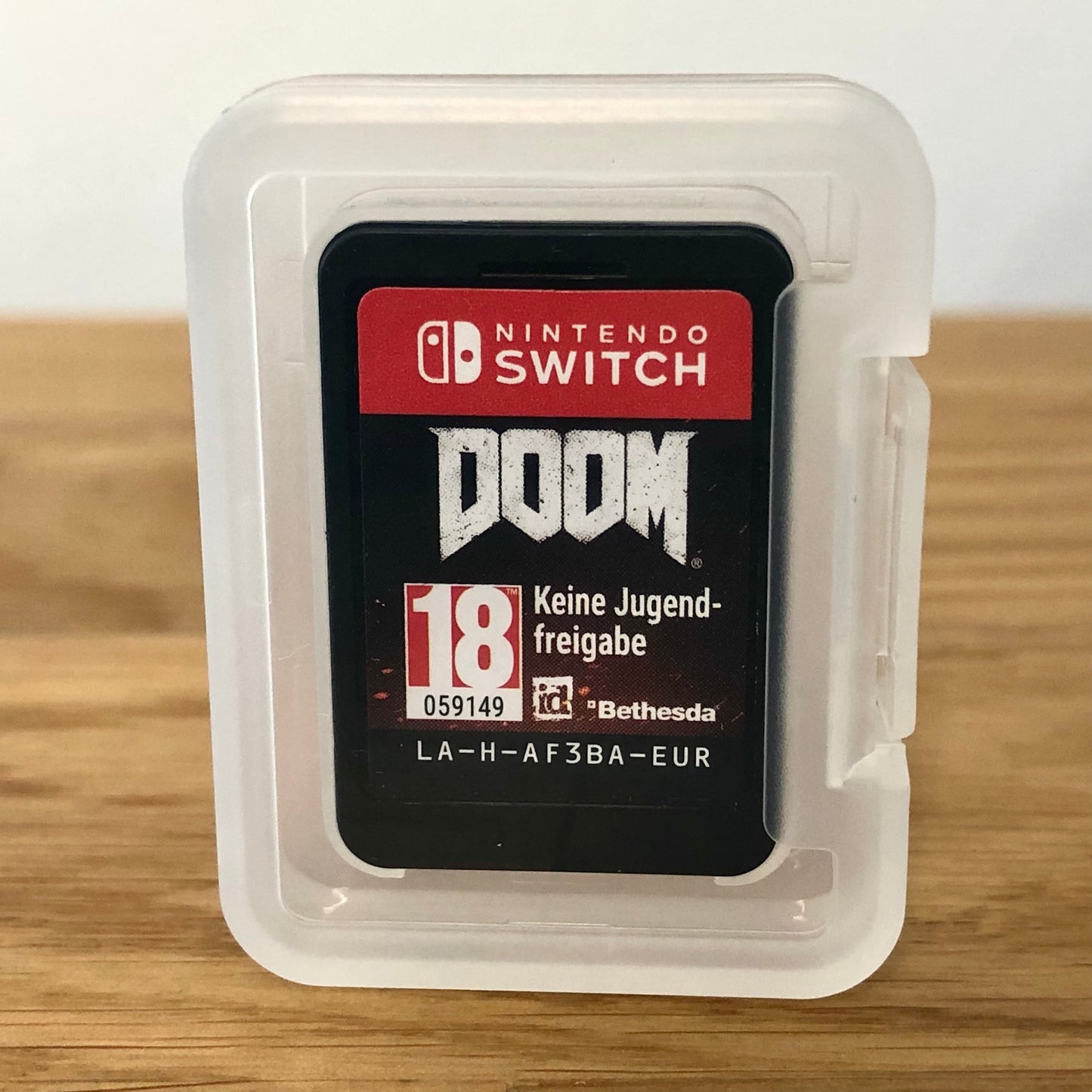 Cartridge of DOOM for Nintendo Switch, the cartridge is inside a cartridge size transparent protective case, through which you can see the front of the cartridge.