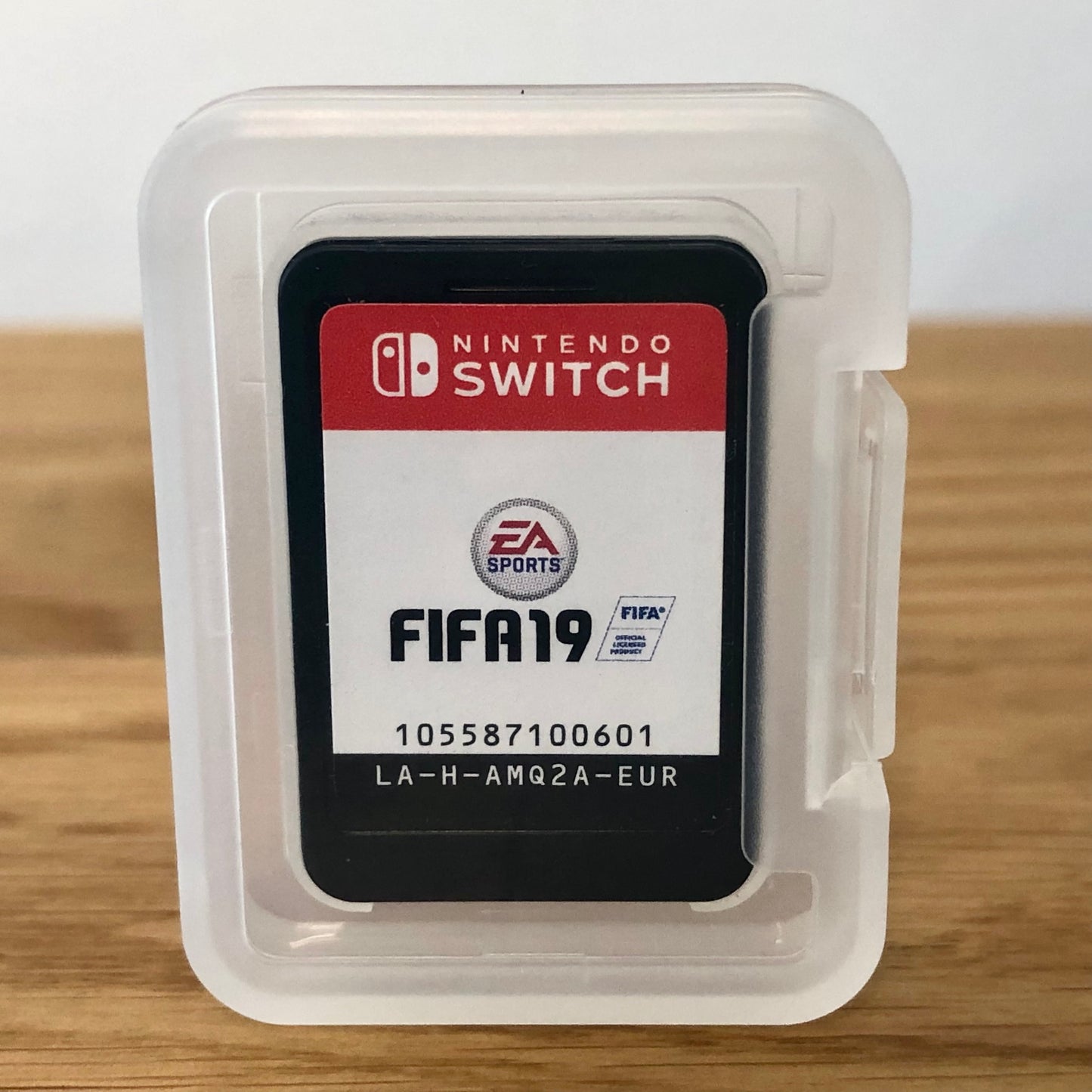 Cartridge of Fifa 19 for Nintendo Switch, the cartridge is inside a cartridge size transparent protective case, through which you can see the front of the cartridge.