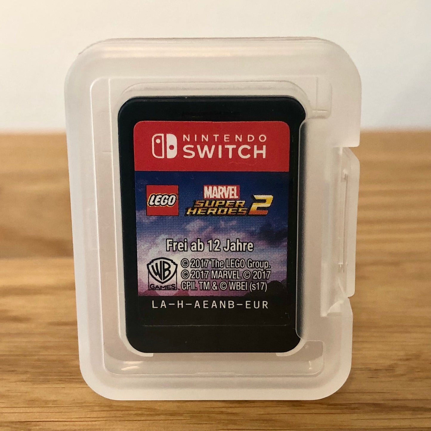 Cartridge of LEGO Marvel Superheroes 2 for Nintendo Switch, the cartridge is inside a cartridge size transparent protective case, through which you can see the front of the cartridge