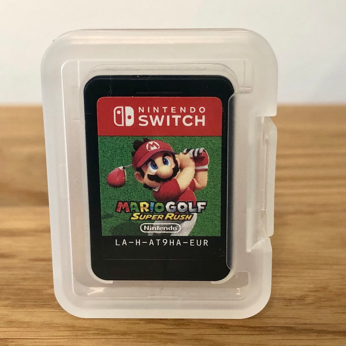 Cartridge of Mario Golf: Super Rush for Nintendo Switch, the cartridge is inside a cartridge size transparent protective case, through which you can see the front of the cartridge