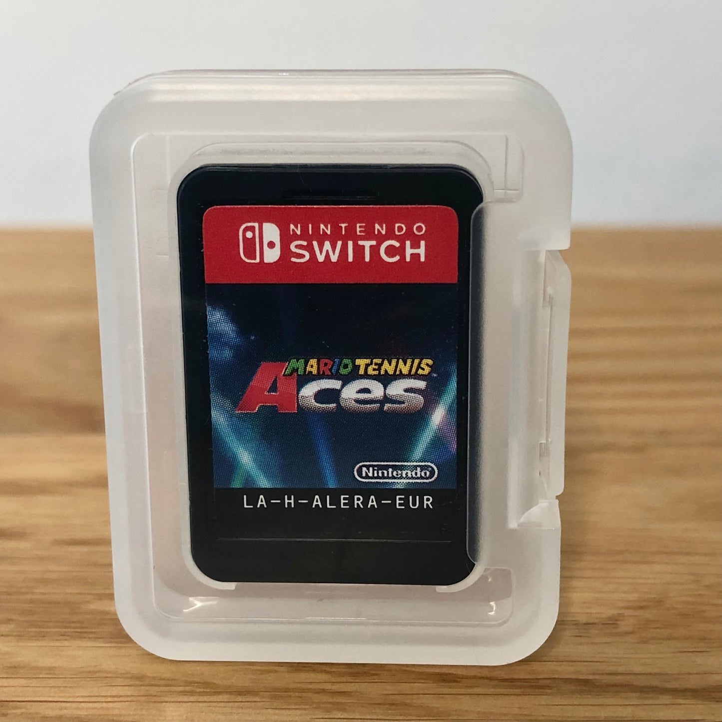 Cartridge of Mario Tennis Aces for Nintendo Switch, the cartridge is inside a cartridge size transparent protective case, through which you can see the front of the cartridge