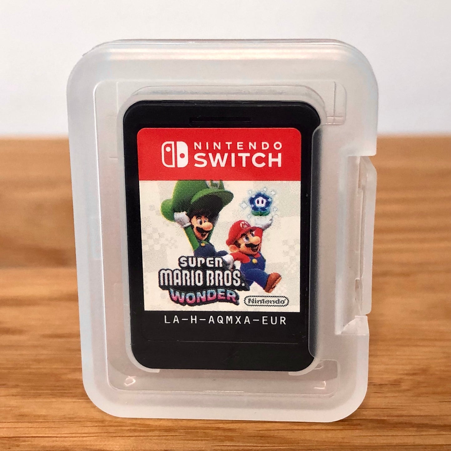 Cartridge of Super Mario Bros. Wonder for Nintendo Switch, the cartridge is inside a cartridge size transparent protective case, through which you can see the front of the cartridge