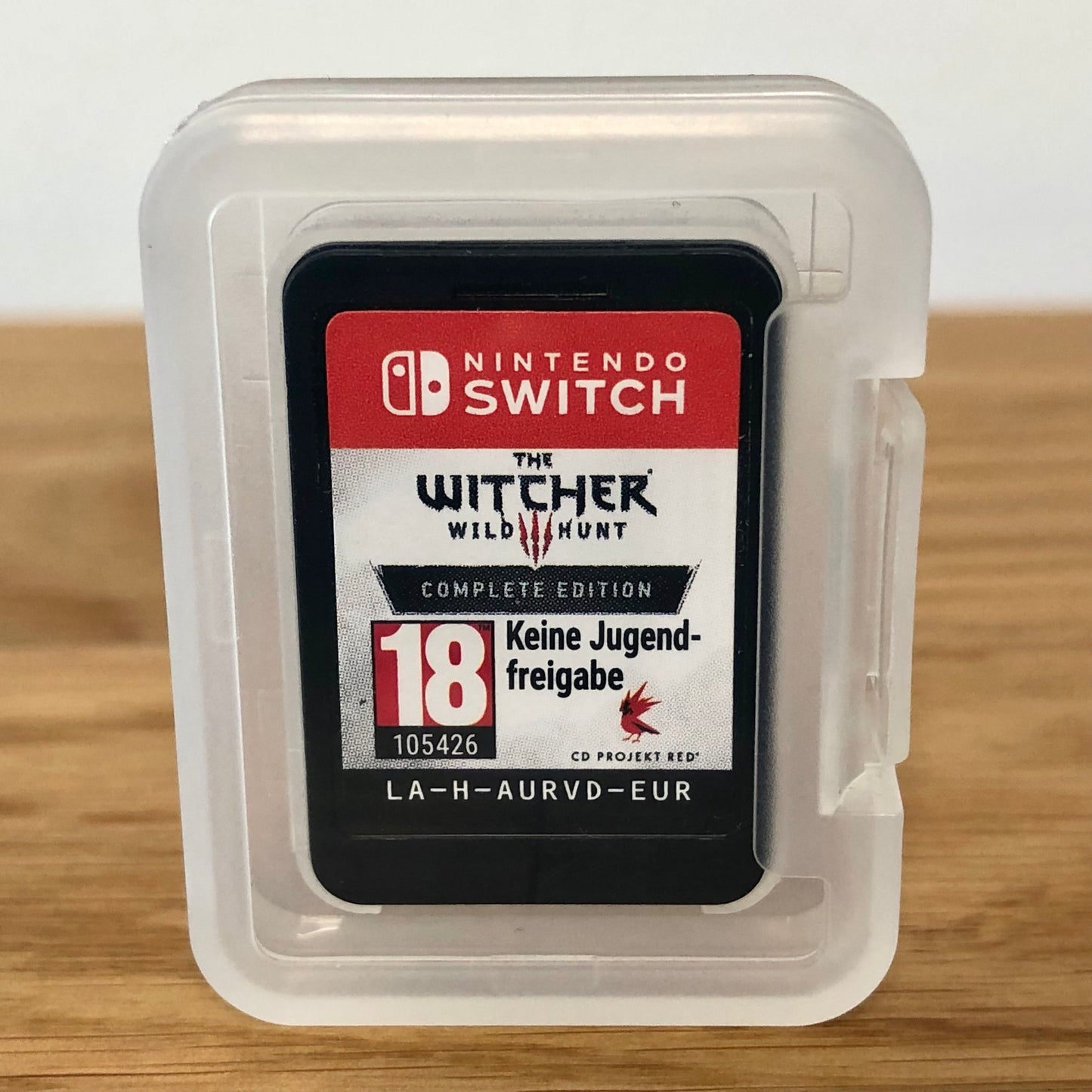Cartridge of The Witcher 3: Wild Hunt Complete Collection for Nintendo Switch, the cartridge is inside a cartridge size transparent protective case, through which you can see the front of the cartridge