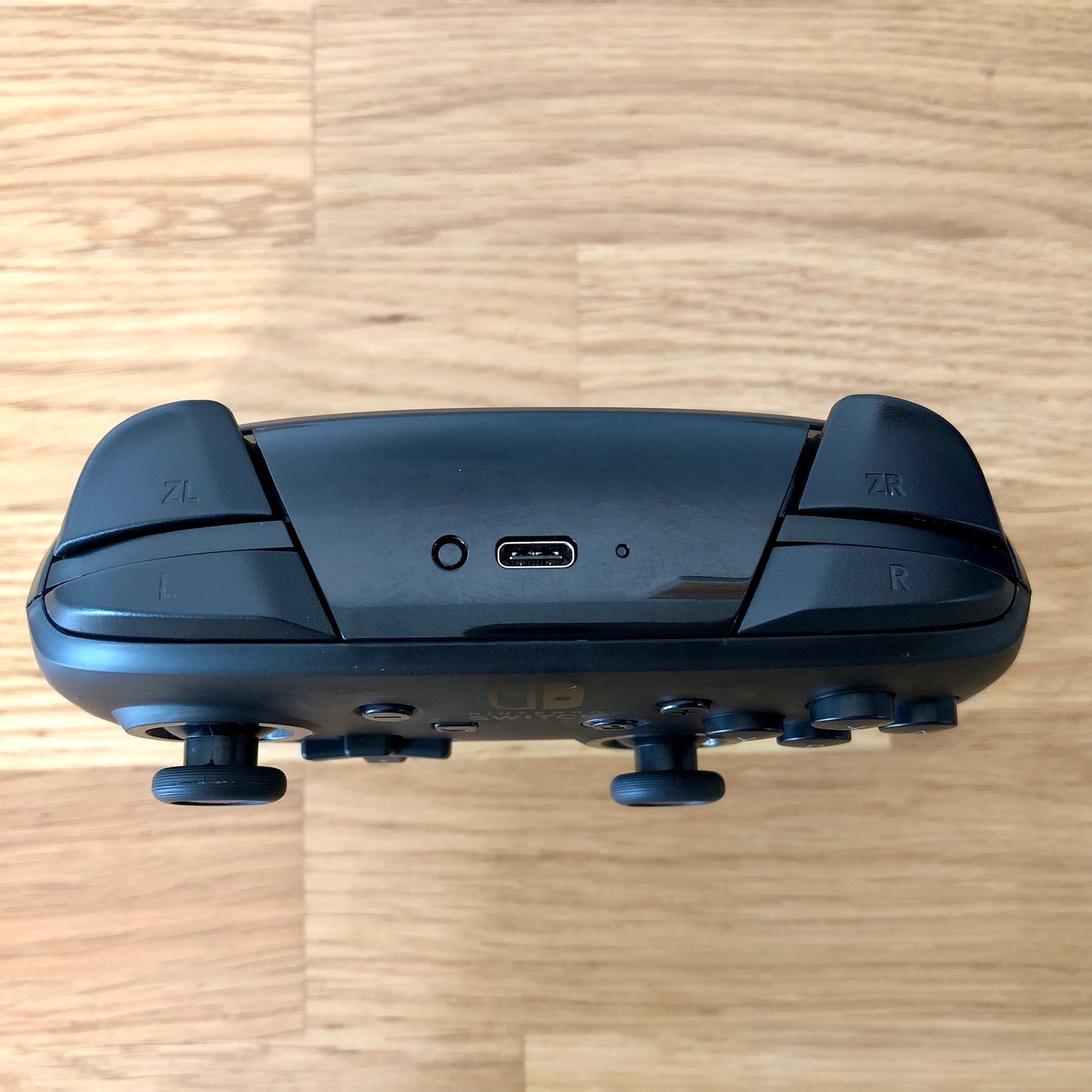 Birds eye top view of Nintendo Switch Pro Controller, highlighting model details and shoulder buttons.