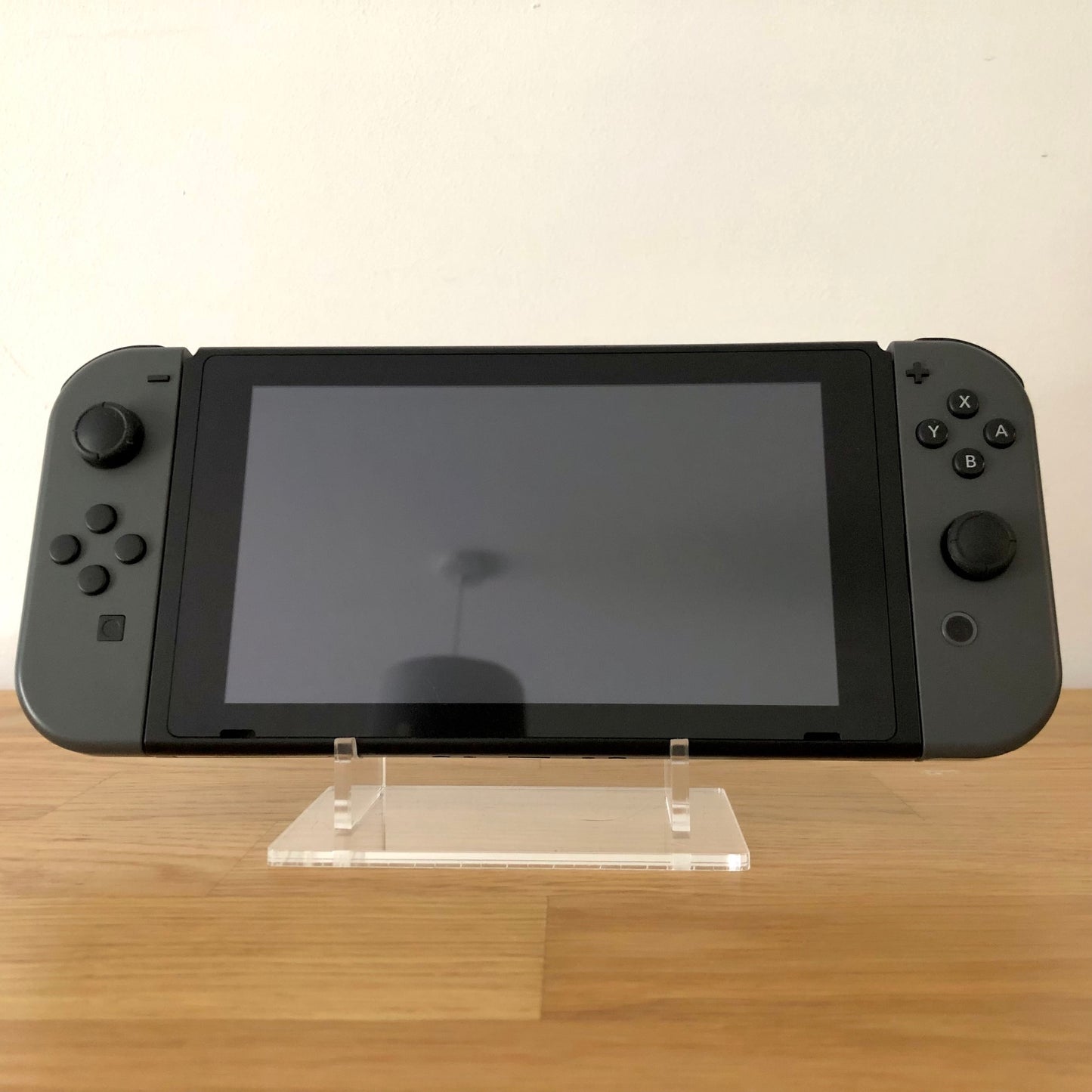 Front view of Nintendo Switch console with grey Joy-Cons attached, showing screen and face button layout.