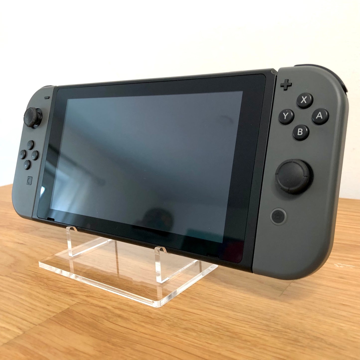 Angled front of Nintendo Switch with grey Joy-Cons, showing full face buttons, control sticks and screen.