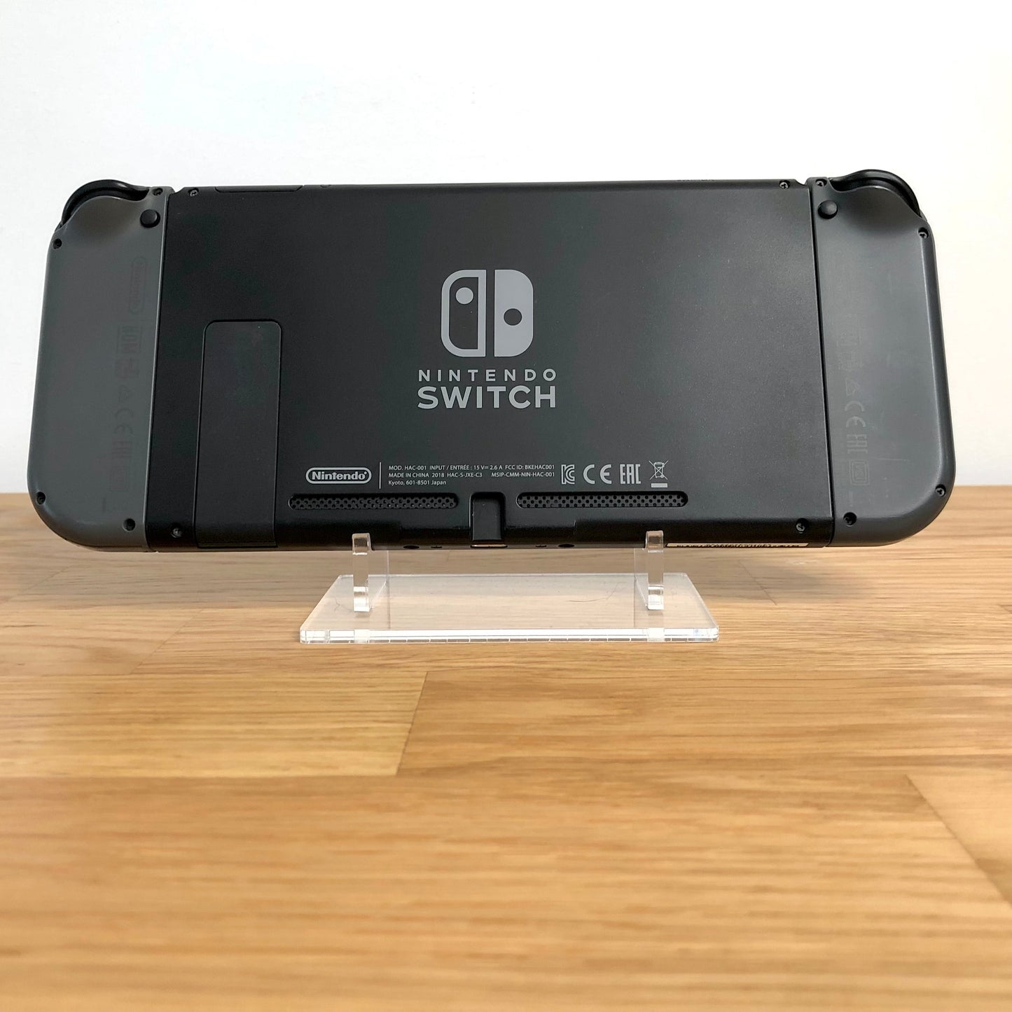 Back of Nintendo Switch console with grey Joy-Cons attached, showing logo, kickstand and trigger buttons.