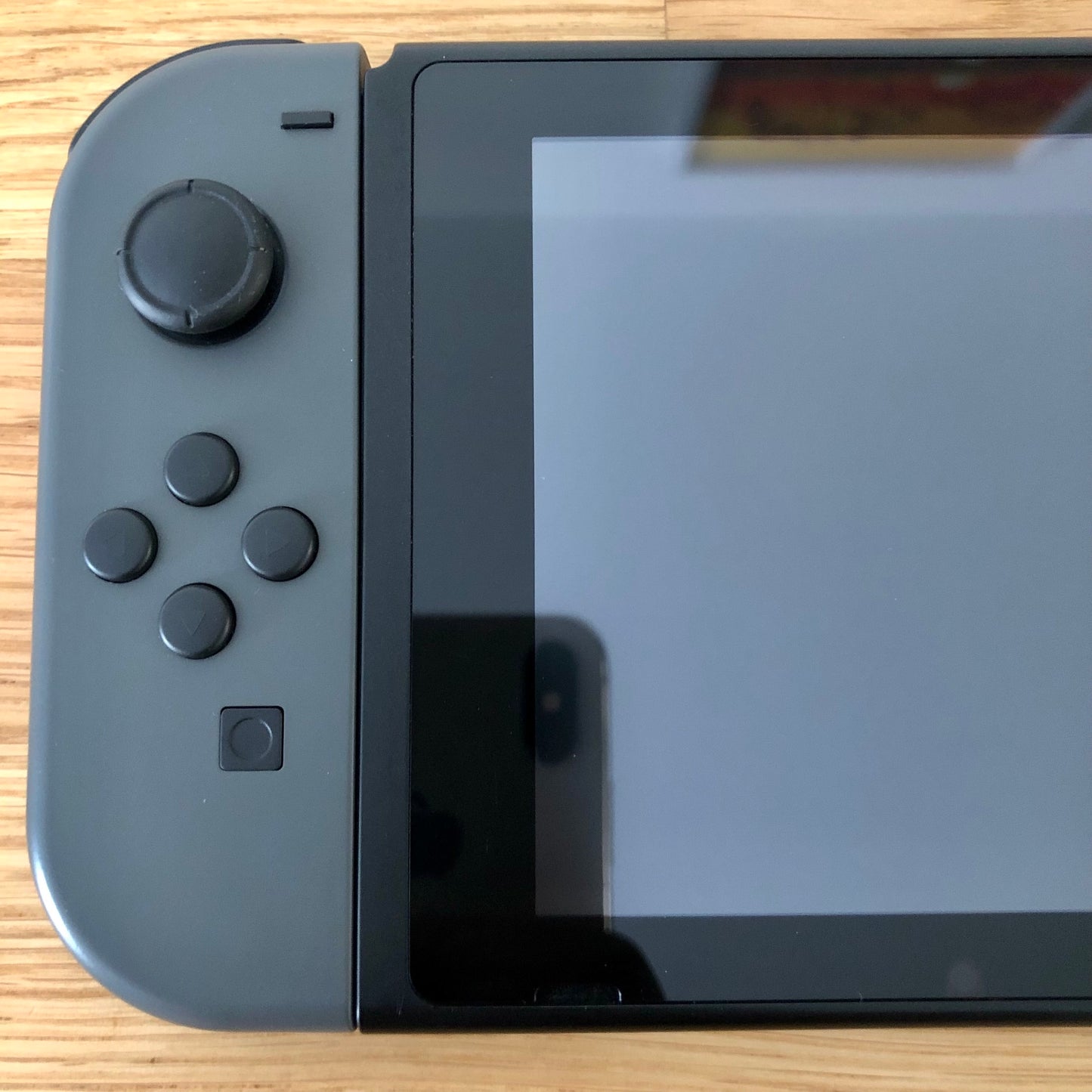 Close-up of grey left Joy-Con on Nintendo Switch, showing D-pad style buttons, stick and capture button.