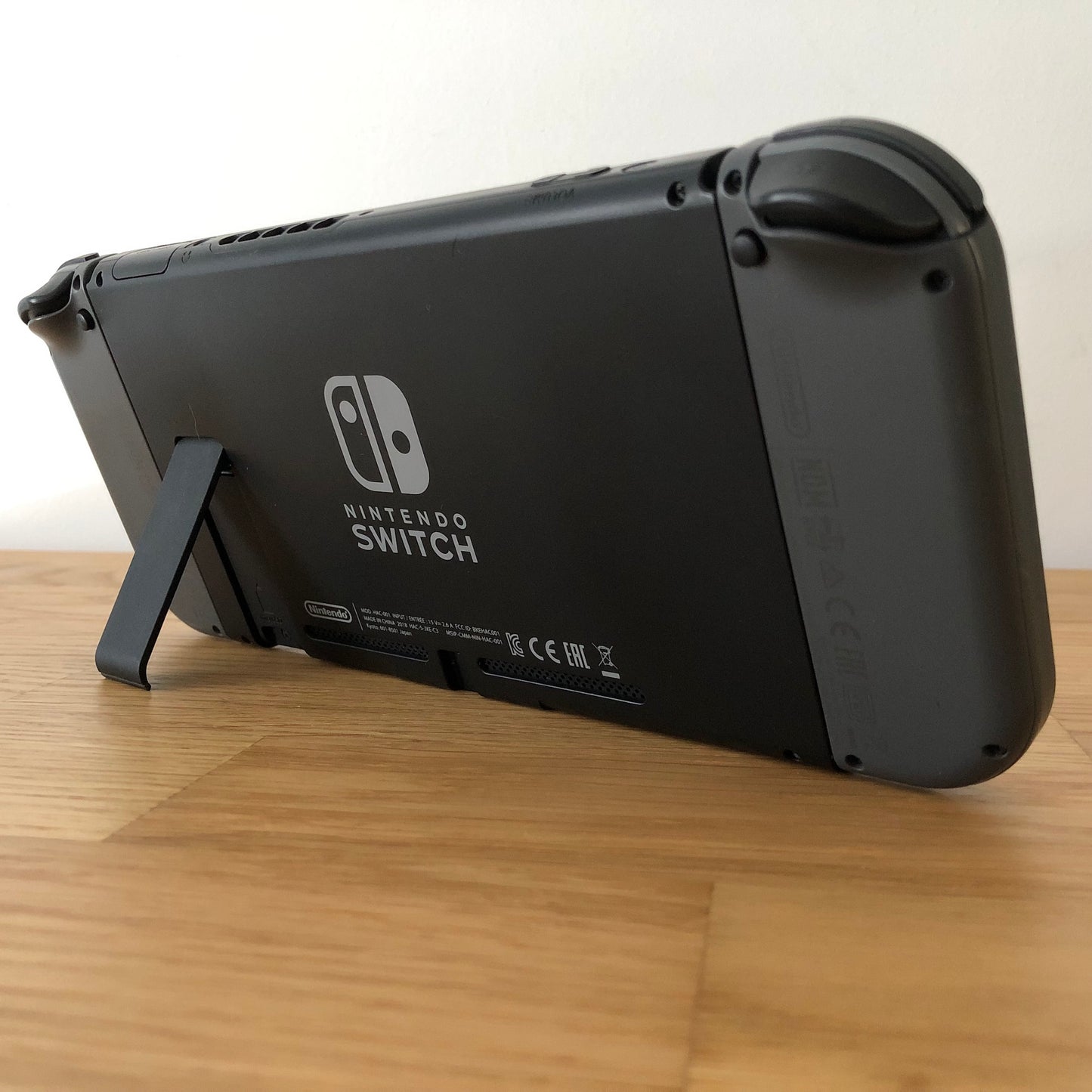 Rear angled view of Nintendo Switch with kickstand open, showing logo, microSD card slot and part of the dock connector.