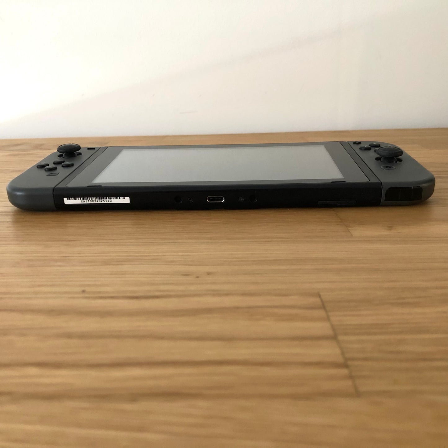 Bottom edge of Nintendo Switch with neon Joy-Cons, showing USB-C port, speaker grills and release buttons.
