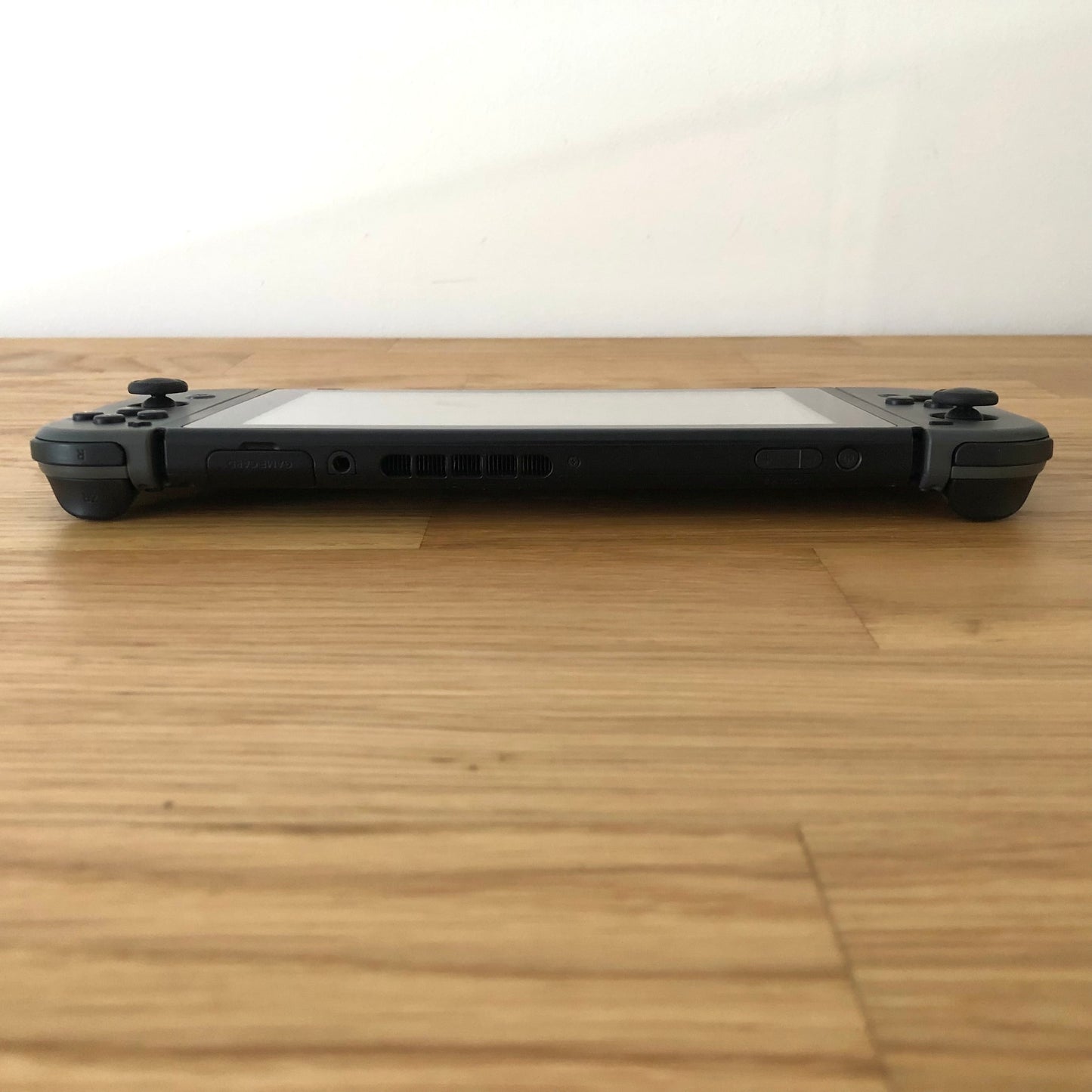Top edge view of Nintendo Switch showing volume, power, card slot and shoulder bumpers with Joy-Cons attached.