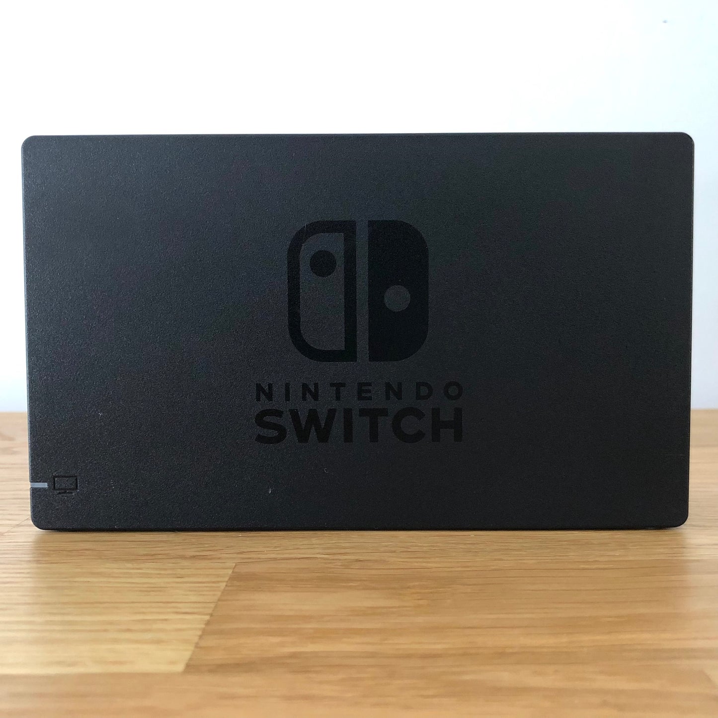 Front of Nintendo Switch dock with embossed logo, smooth matte finish and rounded edges, compatible with neon Joy-Cons.