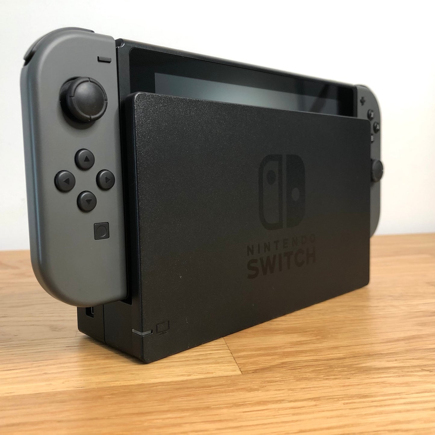 Angled left view of grey Nintendo Switch console docked, showing control sticks and front buttons of Joy-Cons.