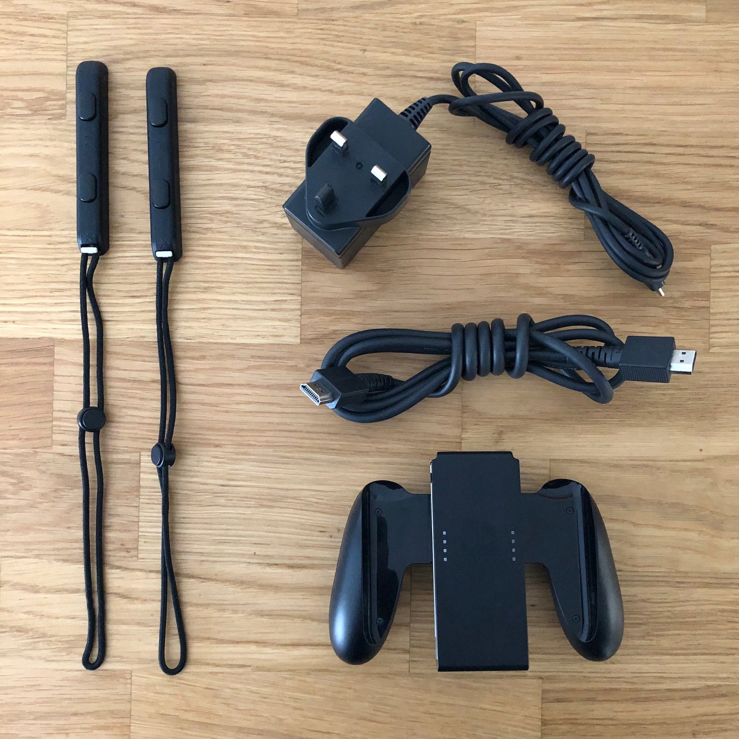 Nintendo Switch accessories including Joy-Con straps, HDMI cable, charger plug and Joy-Con grip laid out.