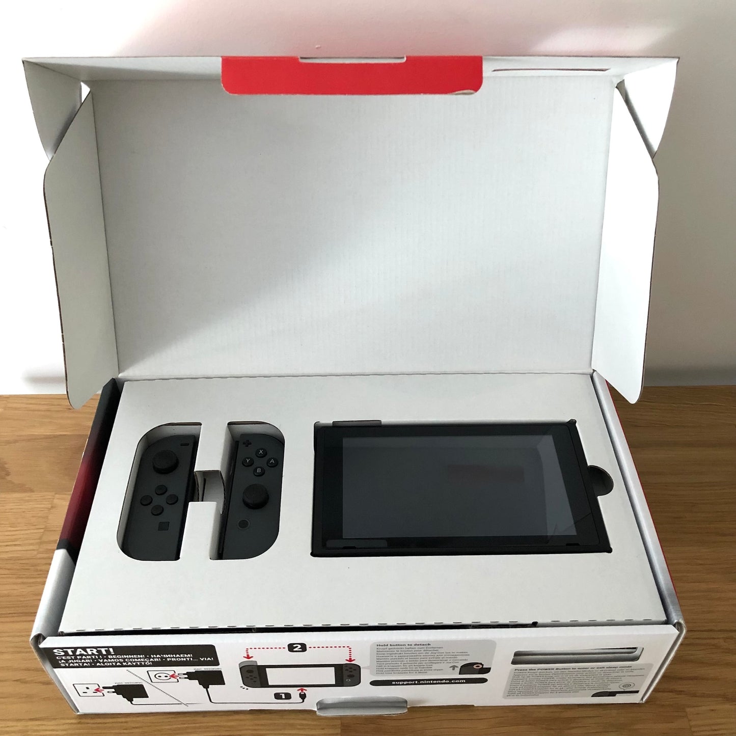 Nintendo Switch console in original box with lid open, showing console and Joy-Cons neatly packed in top tray.