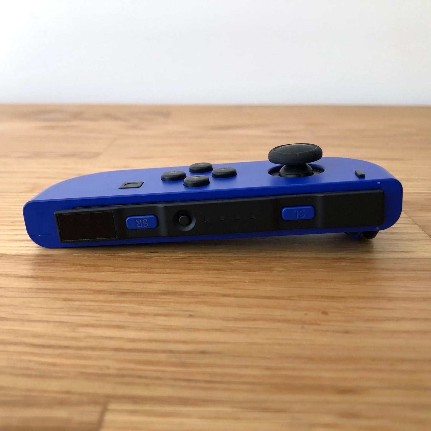 Bottom side view of neon blue Nintendo Switch Joy-Con controller displaying SL, SR, and sync button.