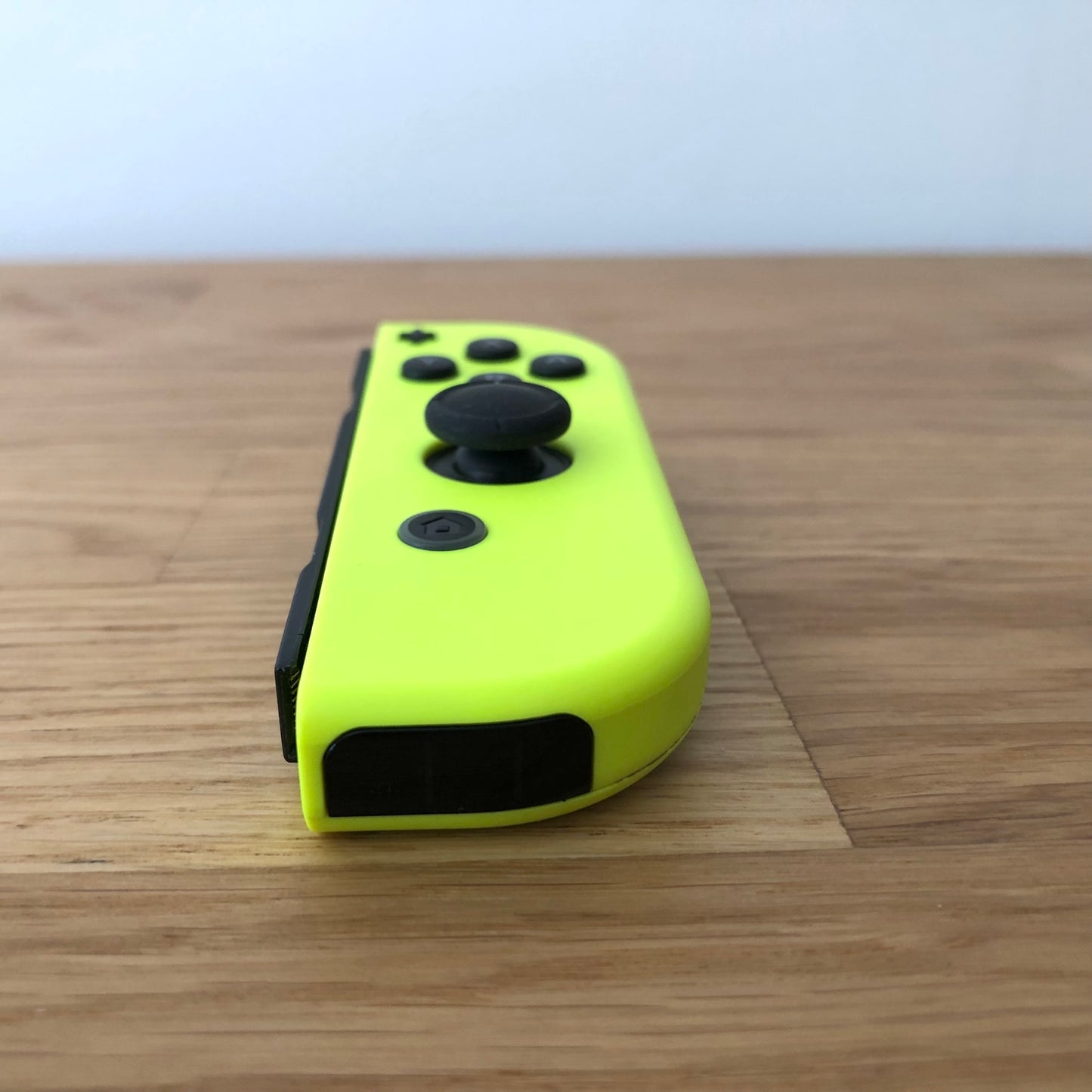Angled front view of Neon YellowNintendo Switch Joy-Con controller showing joystick and home button.