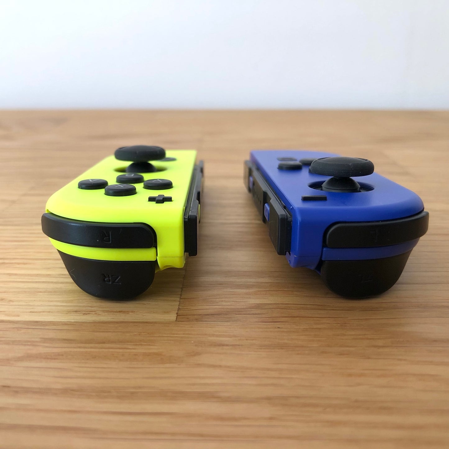 Angled view of neon yellow and blue Nintendo Switch Joy-Con controllers showing ZR and ZL trigger buttons.