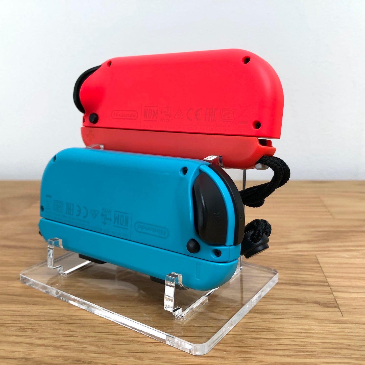 Angled rear view of neon red and blue Joy-Con controllers for Nintendo Switch, showing shoulder buttons.
