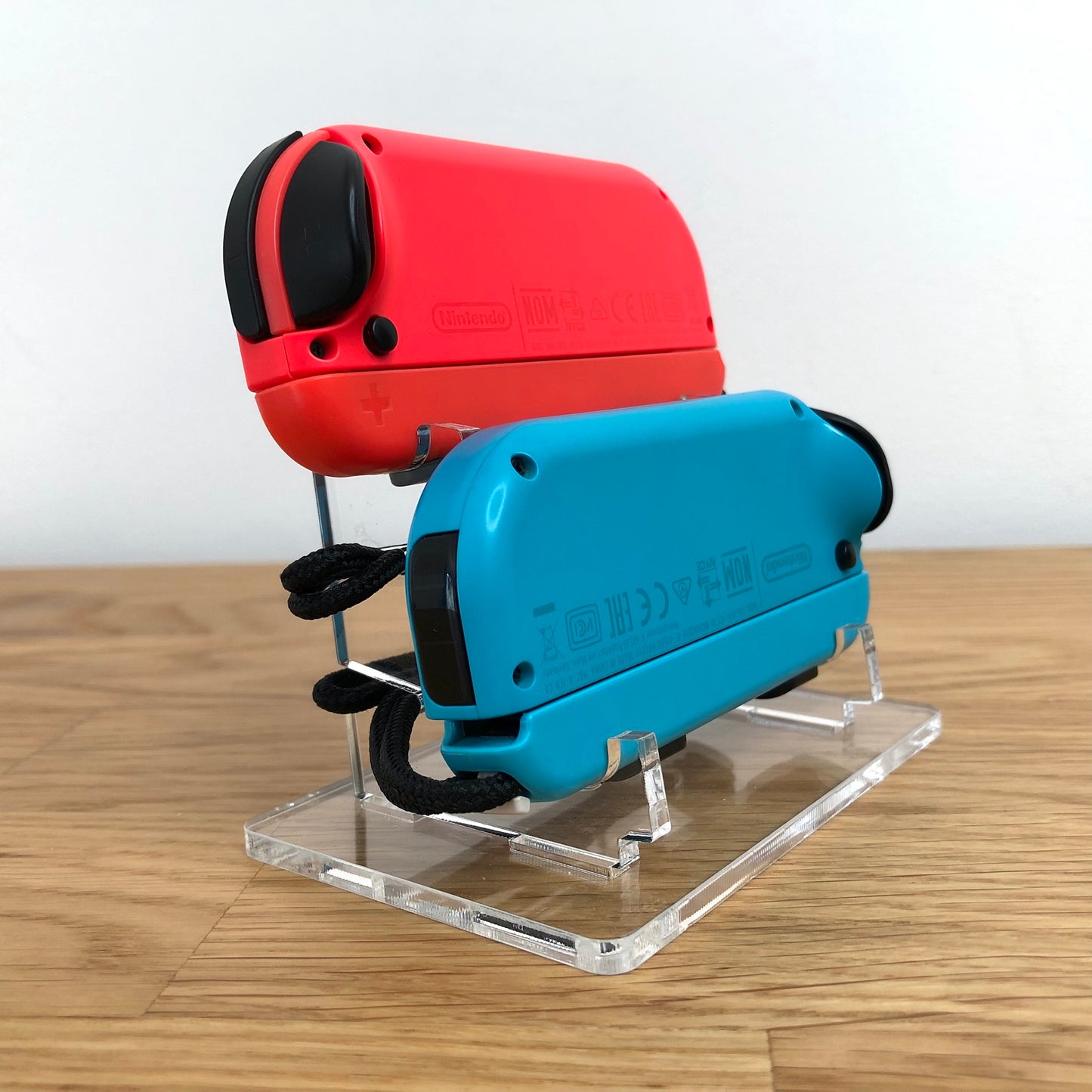 Side angle showing back of neon red and blue Nintendo Switch Joy-Con controllers on a stand.
