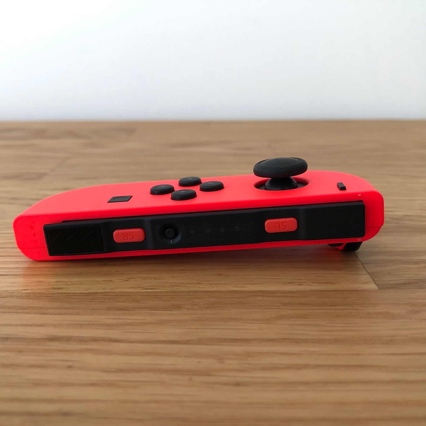 Bottom edge view of neon red Nintendo Switch Joy-Con controller, showing SL and SR buttons clearly.