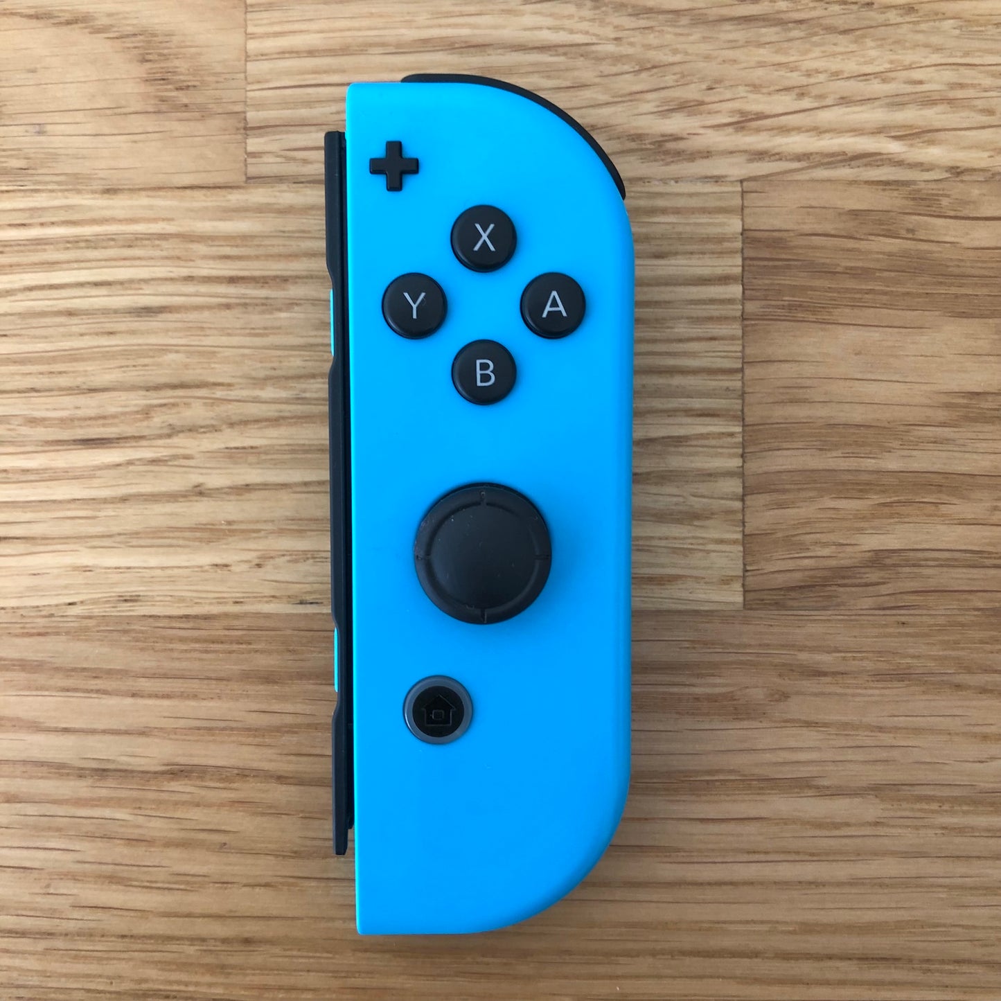 Top-down view of neon blue Nintendo Switch Joy-Con controller with full button layout visible.