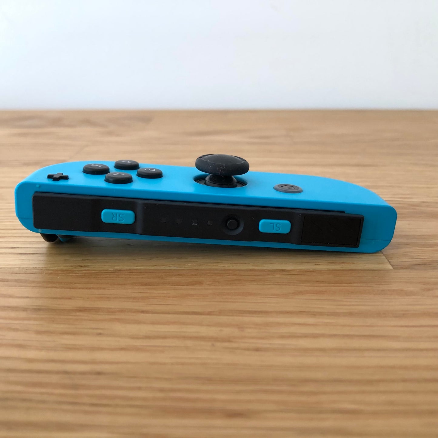 Bottom side view of neon blue Nintendo Switch Joy-Con controller displaying SL, SR, and sync button.