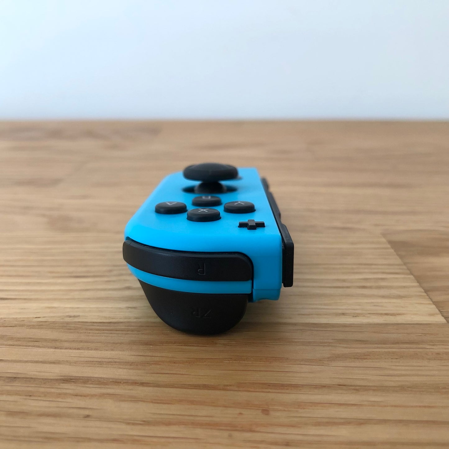 Rear angle of neon blue Nintendo Switch Joy-Con controller focusing on ZR and curved grip area.
