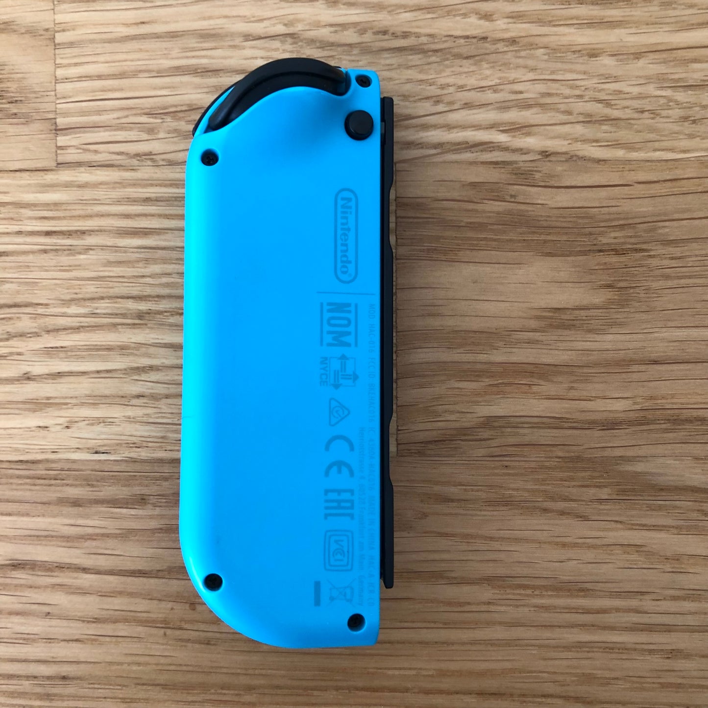 Back view of neon blue Nintendo Switch Joy-Con controller displaying branding and model information.