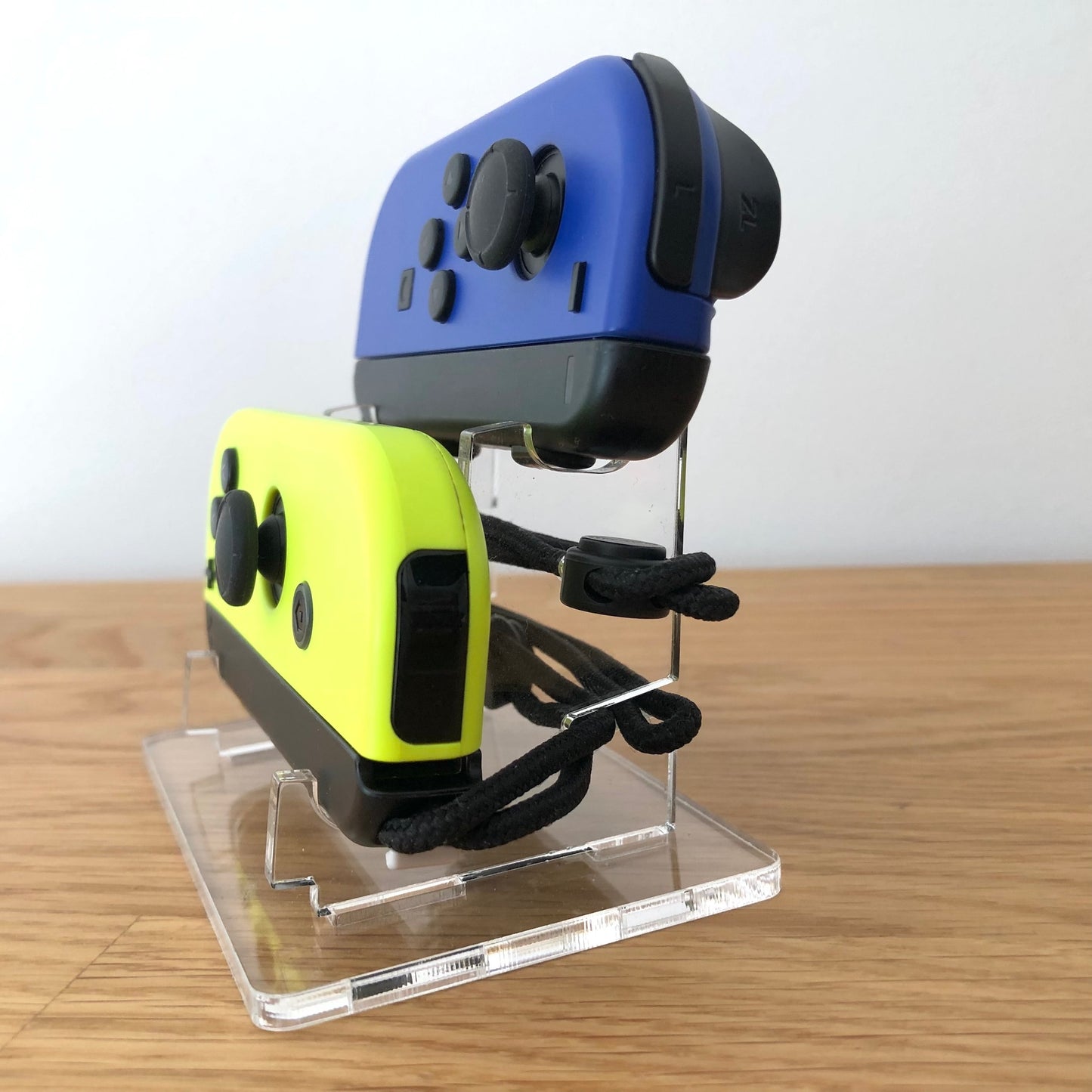 Angled view of neon blue and yellow Joy-Con controllers on display stand, showing full button layout.