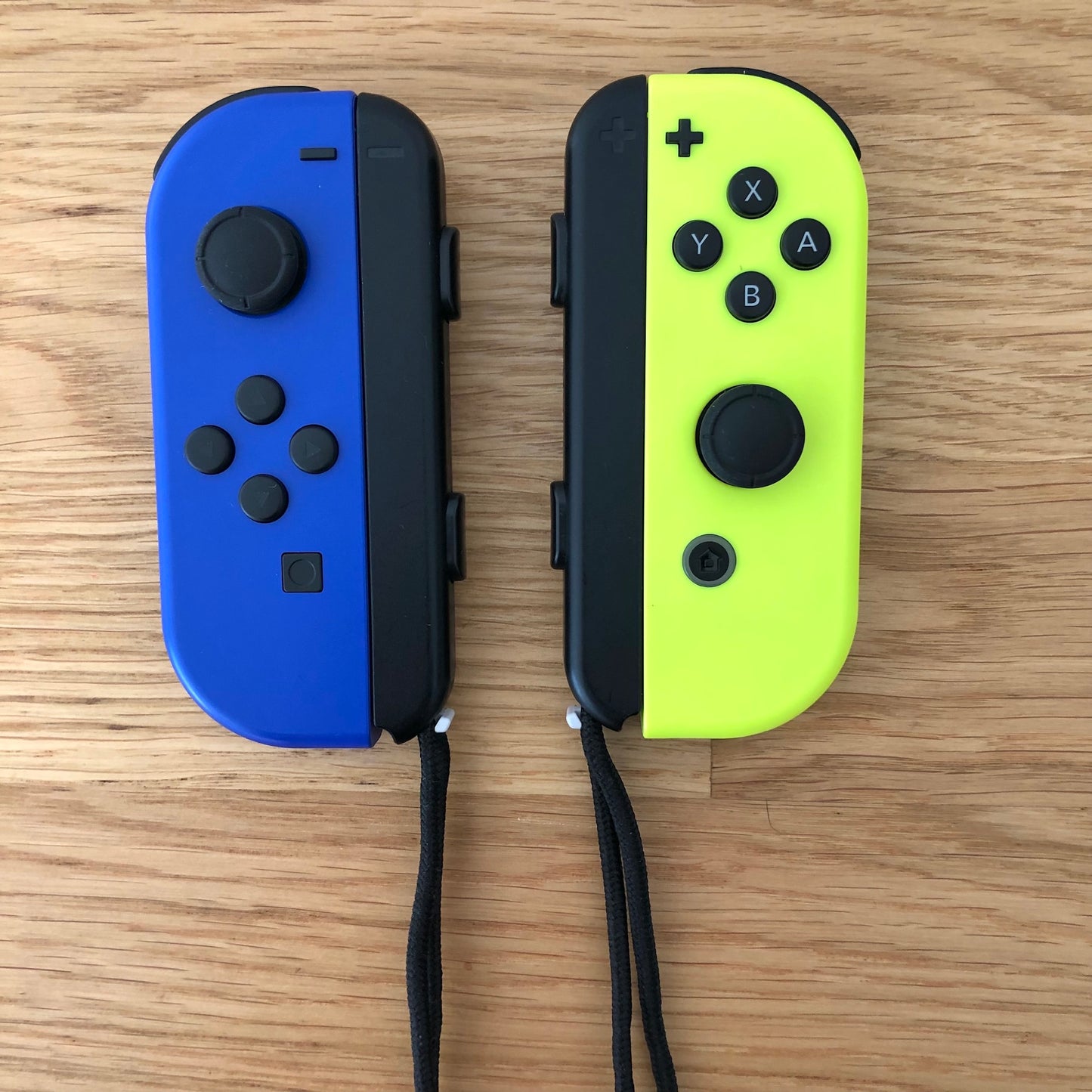 Birds eye top view of Blue & Neon Yellow Joy-Cons pair with supporting wrist straps attached, showing button layout and design.