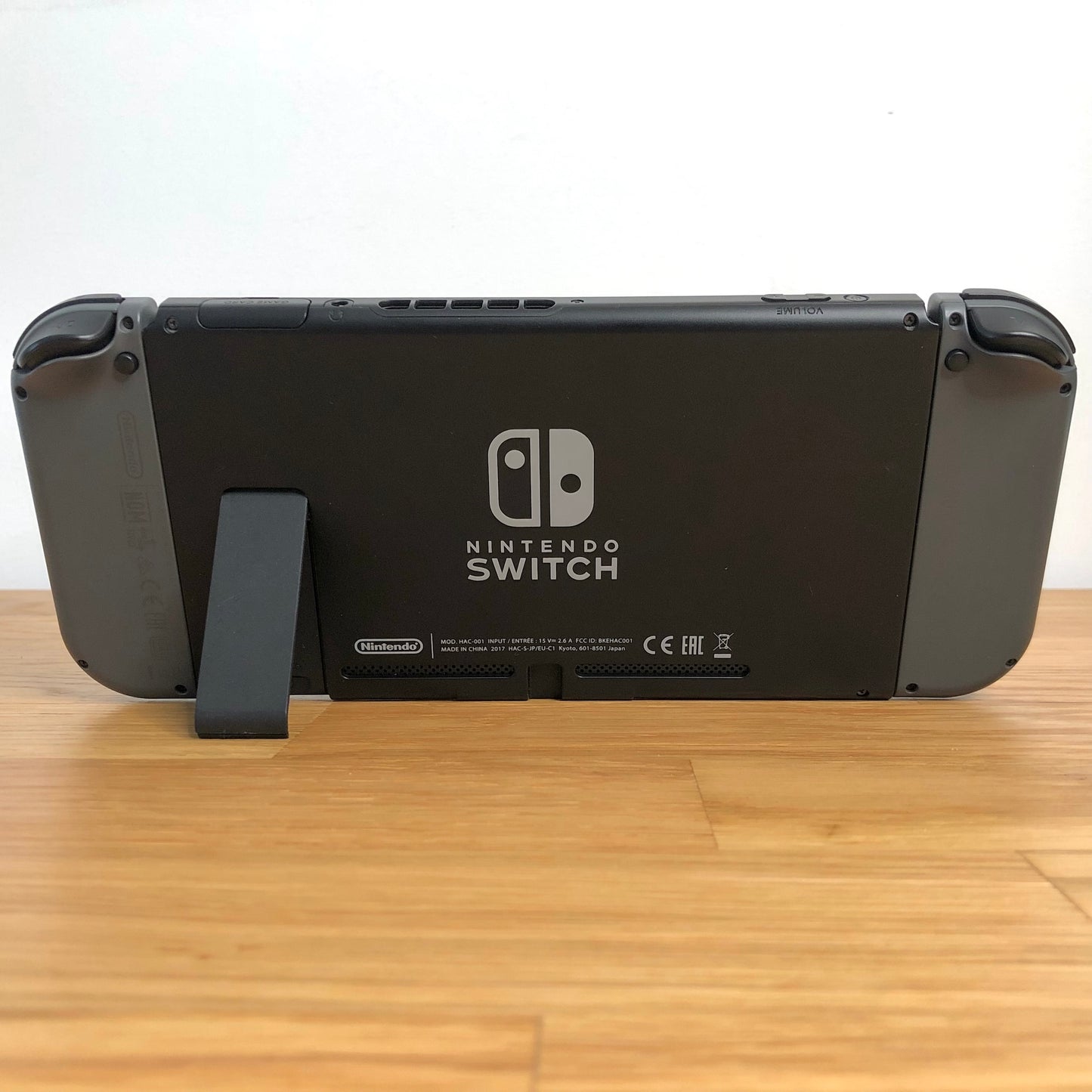 Back of Nintendo Switch console with Joy-Cons attached, showing logo, serial info, triggers and kickstand open.