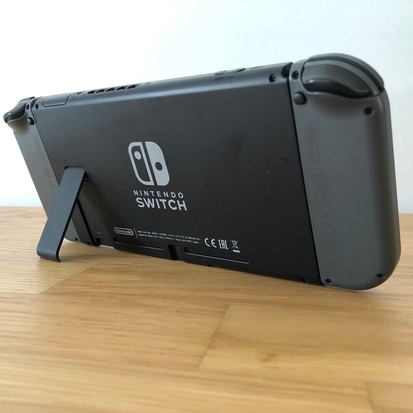 Back angled of Nintendo Switch console with Joy-Cons attached, showing logo, serial info, triggers and kickstand open.