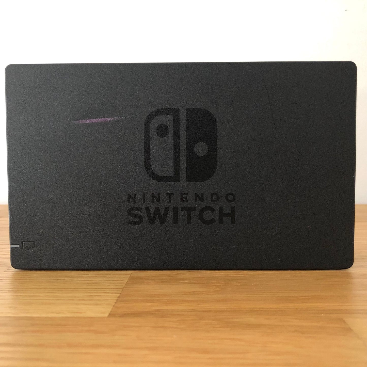 Front of grey Nintendo Switch dock with embossed Nintendo Switch logo, smooth matte finish and rounded edges.
