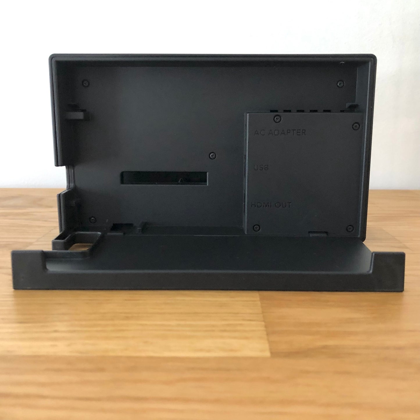 Inside of grey Nintendo Switch dock with flap open, showing ports for AC adapter, HDMI out and LAN.