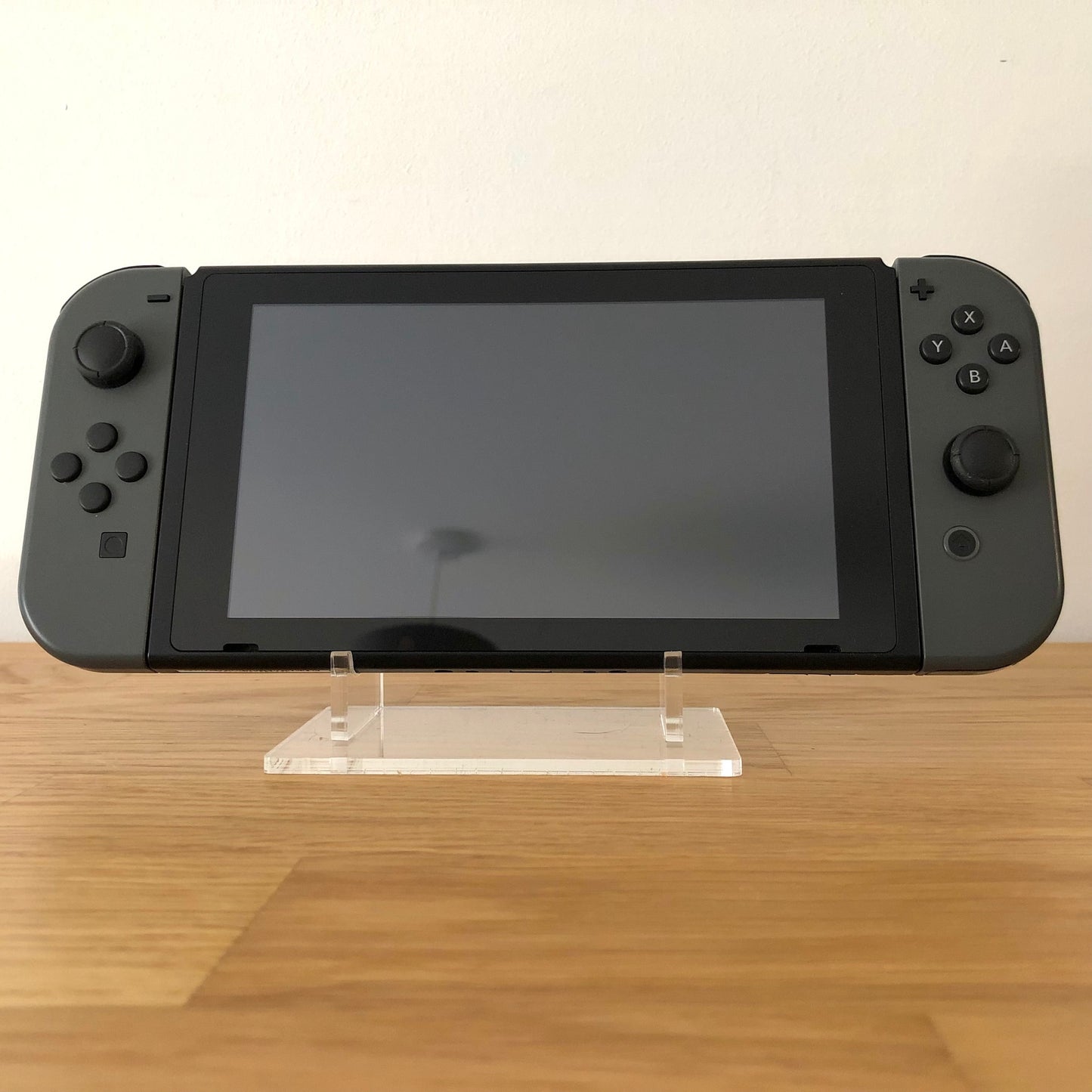 Front view of Nintendo Switch console with grey Joy-Cons attached, showing screen and face button layout.