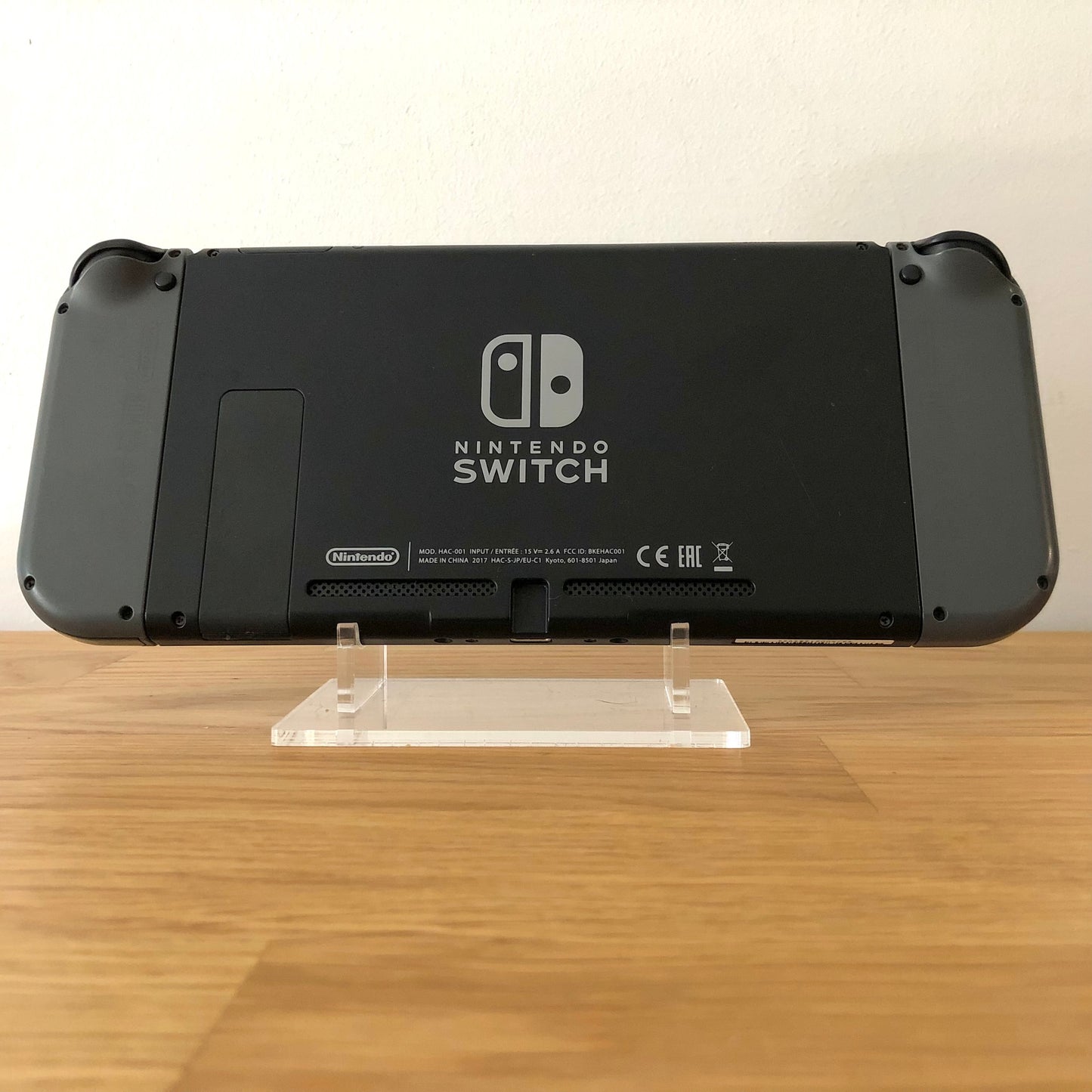 Back of Nintendo Switch console with grey Joy-Cons attached, showing logo, kickstand and trigger buttons.