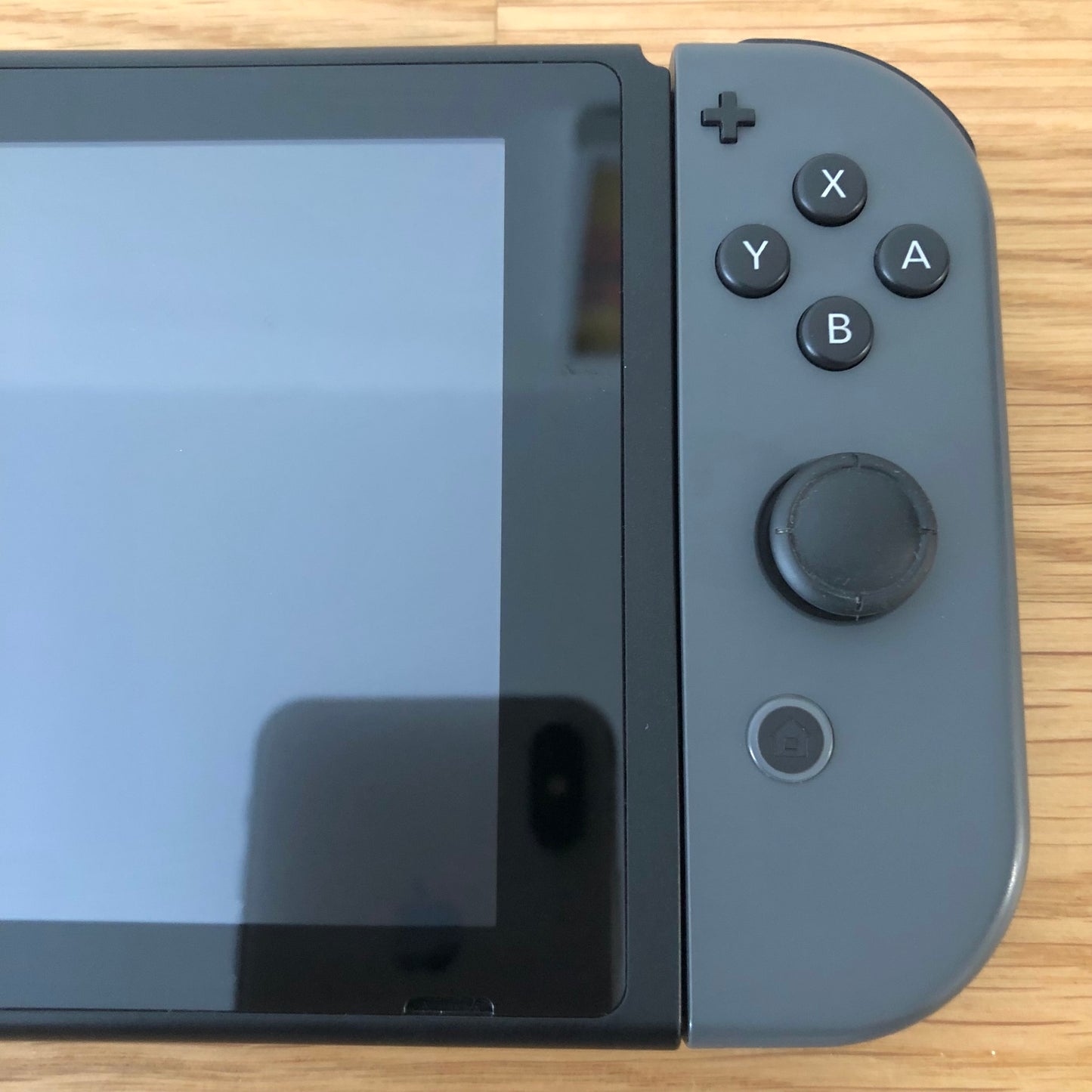 Close-up of grey right Joy-Con on Nintendo Switch, showing A, B, X, Y buttons, stick, plus and home button.