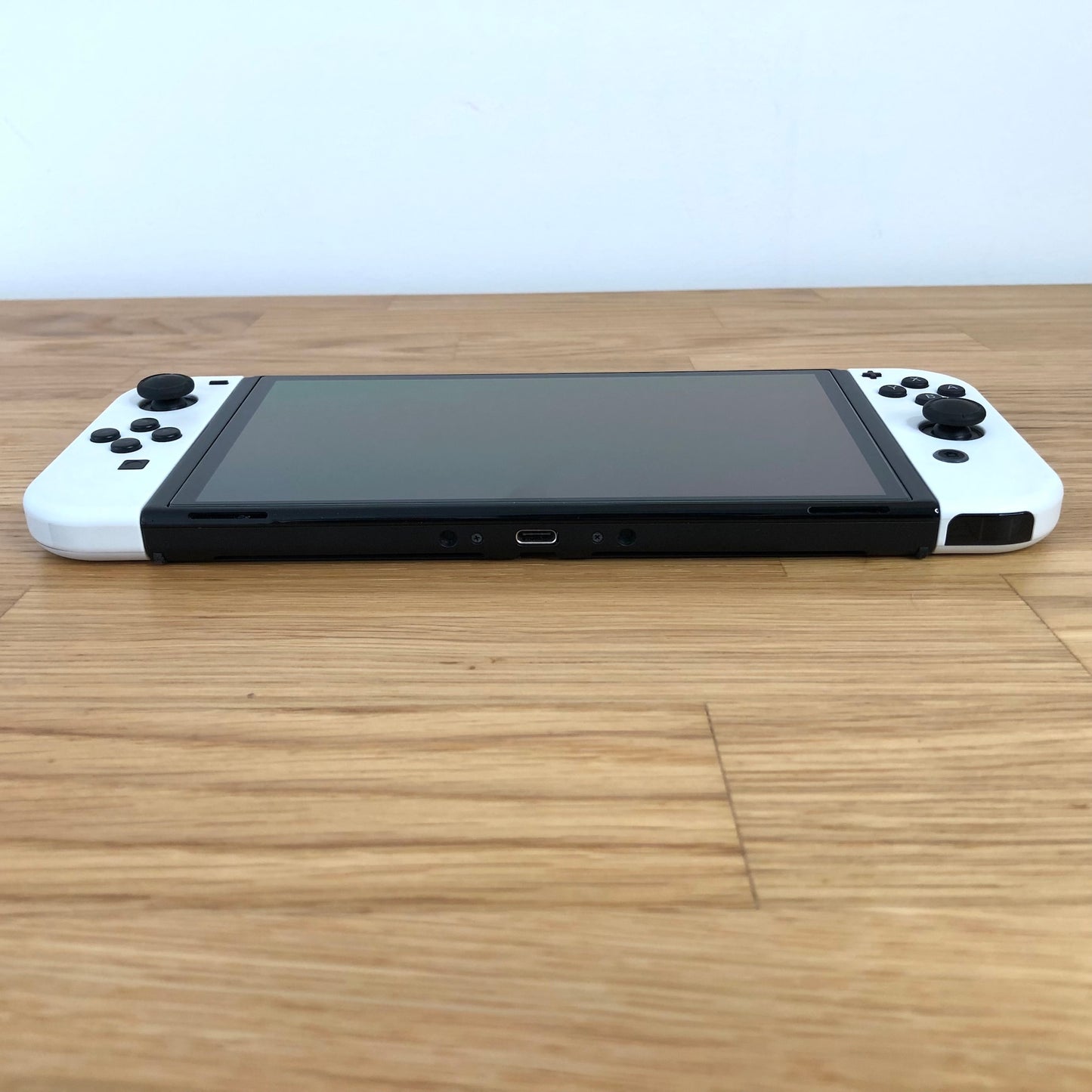 Bottom edge of Nintendo Switch OLED console showing USB-C charging port and Joy-Cons attached.