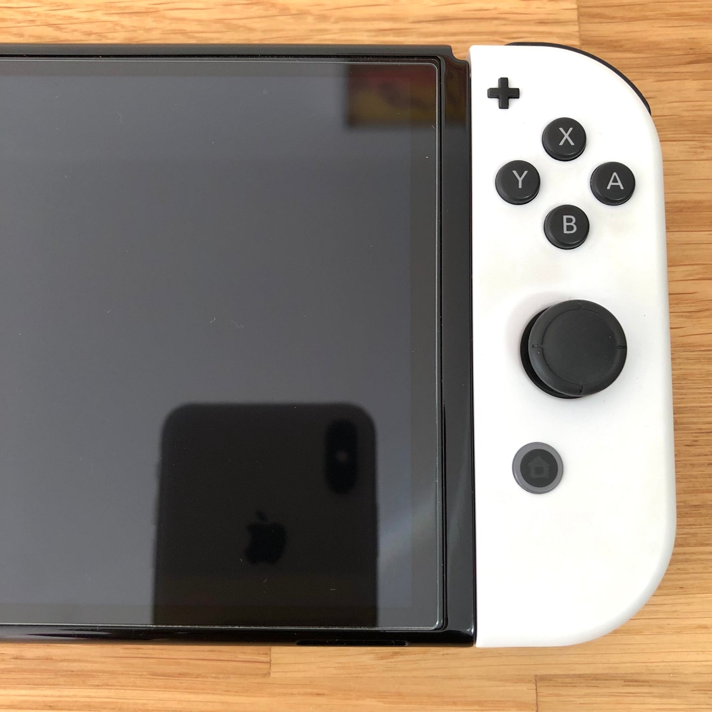 Close-up of right side of Nintendo Switch OLED screen with white Joy-Con showing buttons and control stick.