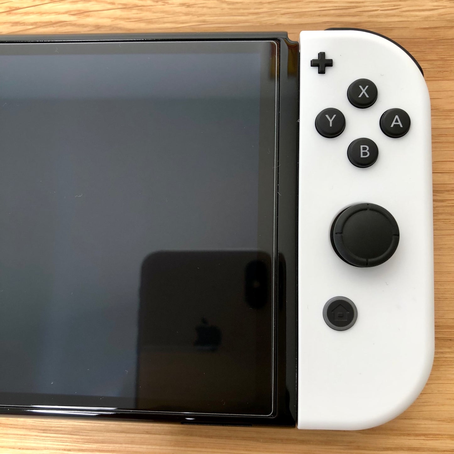Close-up of white right Joy-Con on Nintendo Switch OLED, showing A, B, X, Y buttons, right stick, plus and home.