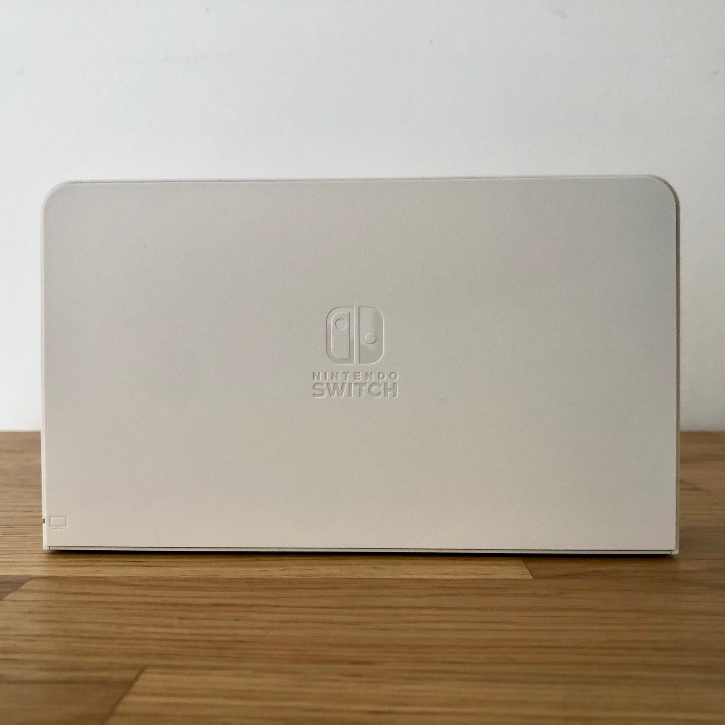 Front of white Nintendo Switch OLED dock with embossed Nintendo Switch logo, smooth matte finish and rounded edges.