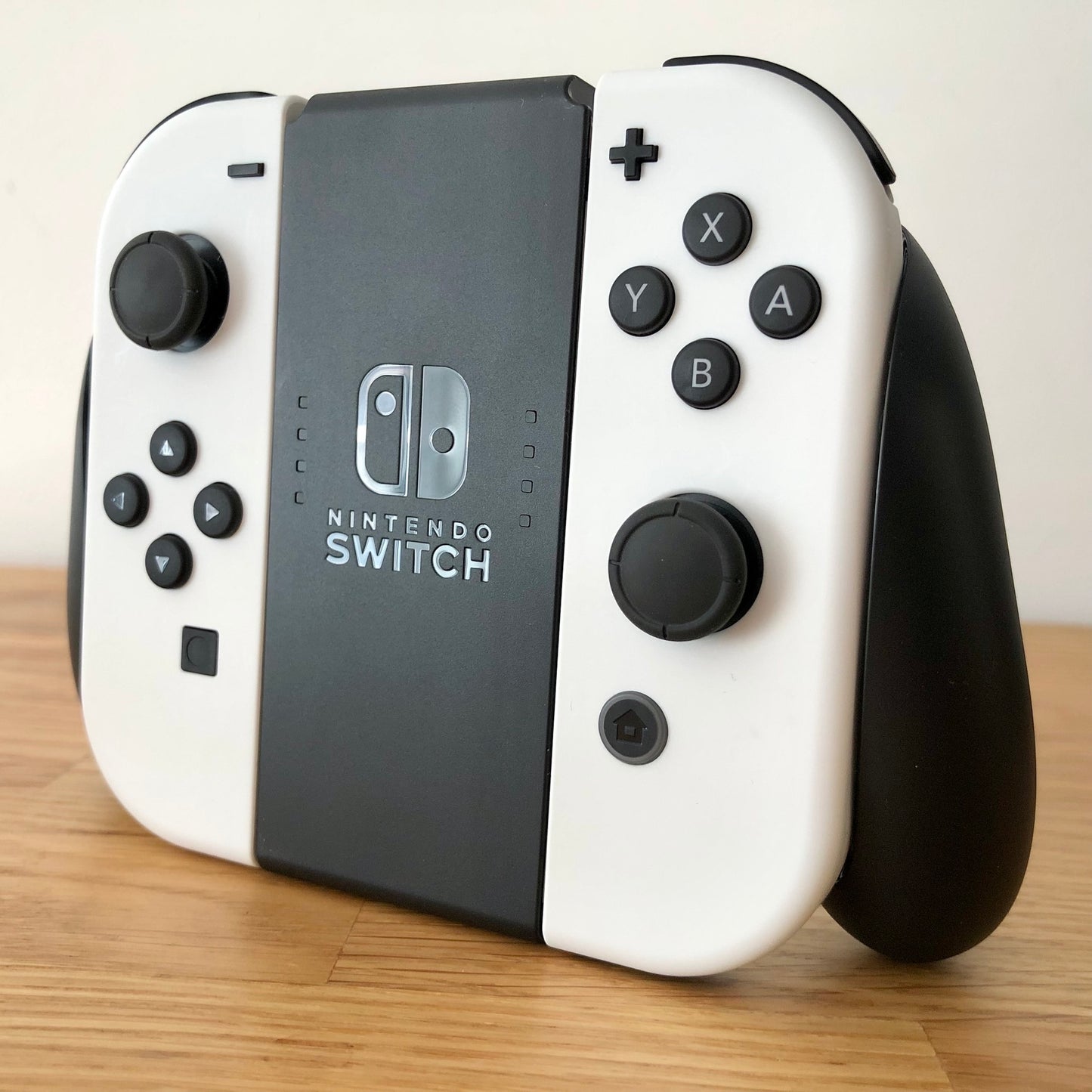 Angled view of Nintendo Switch Joy-Con grip with two White Joy-Cons attached, with visible buttons and sticks.