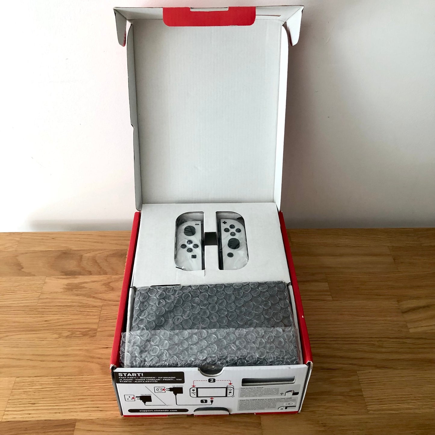 Nintendo Switch OLED console in original box with top open, showing console and Joy-Cons neatly packed in protective tray