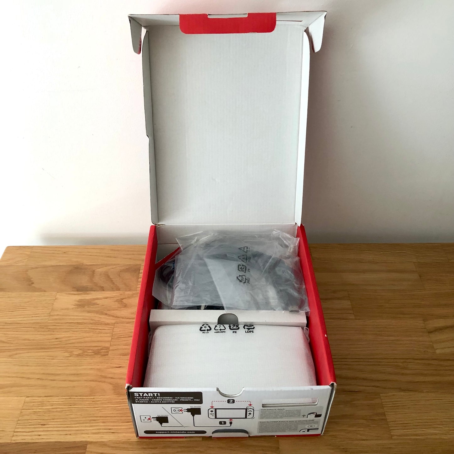 Second layer of Nintendo Switch OLED box showing dock, Joy-Con grip, HDMI cable, charger and straps securely packed.