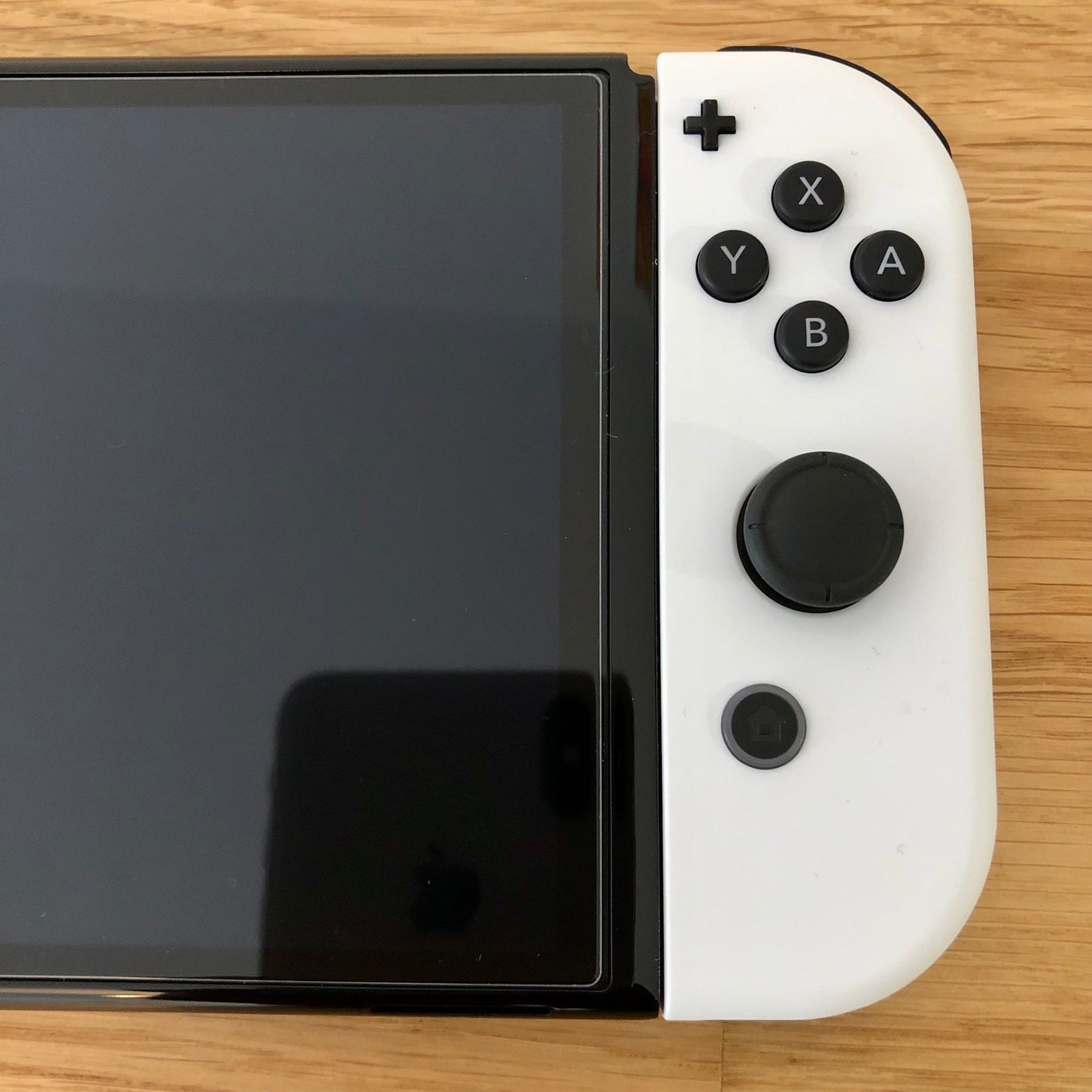 Close-up of white right Joy-Con on Nintendo Switch OLED, showing A, B, X, Y buttons, right stick, plus and home.