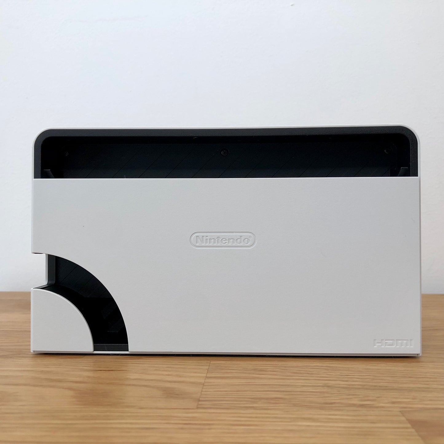 Rear of white Nintendo Switch OLED dock with HDMI branding and Nintendo logo, cable slot openings on left side.
