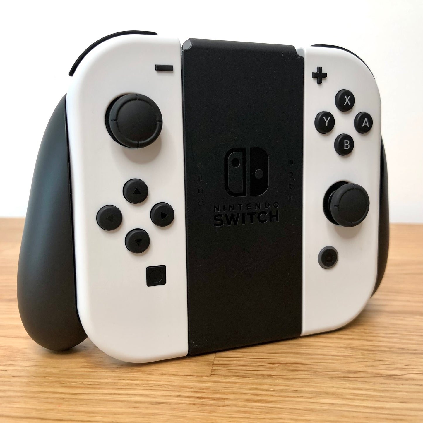Angled view of Joy-Con grips for Nintendo Switch with white Joy-Cons attached, showing condition with all face buttons visible.
