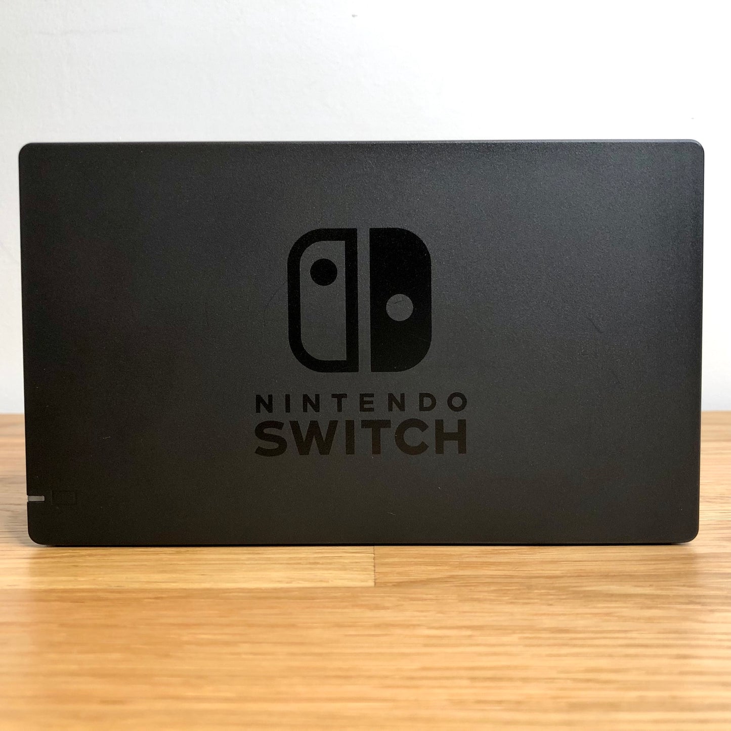 Front of grey Nintendo Switch dock with embossed Nintendo Switch logo, smooth matte finish and rounded edges.